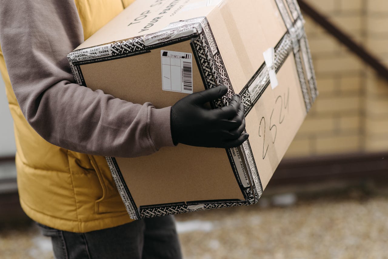Courier holding a package marked TOP PACKAGING wearing gloves for safe delivery.